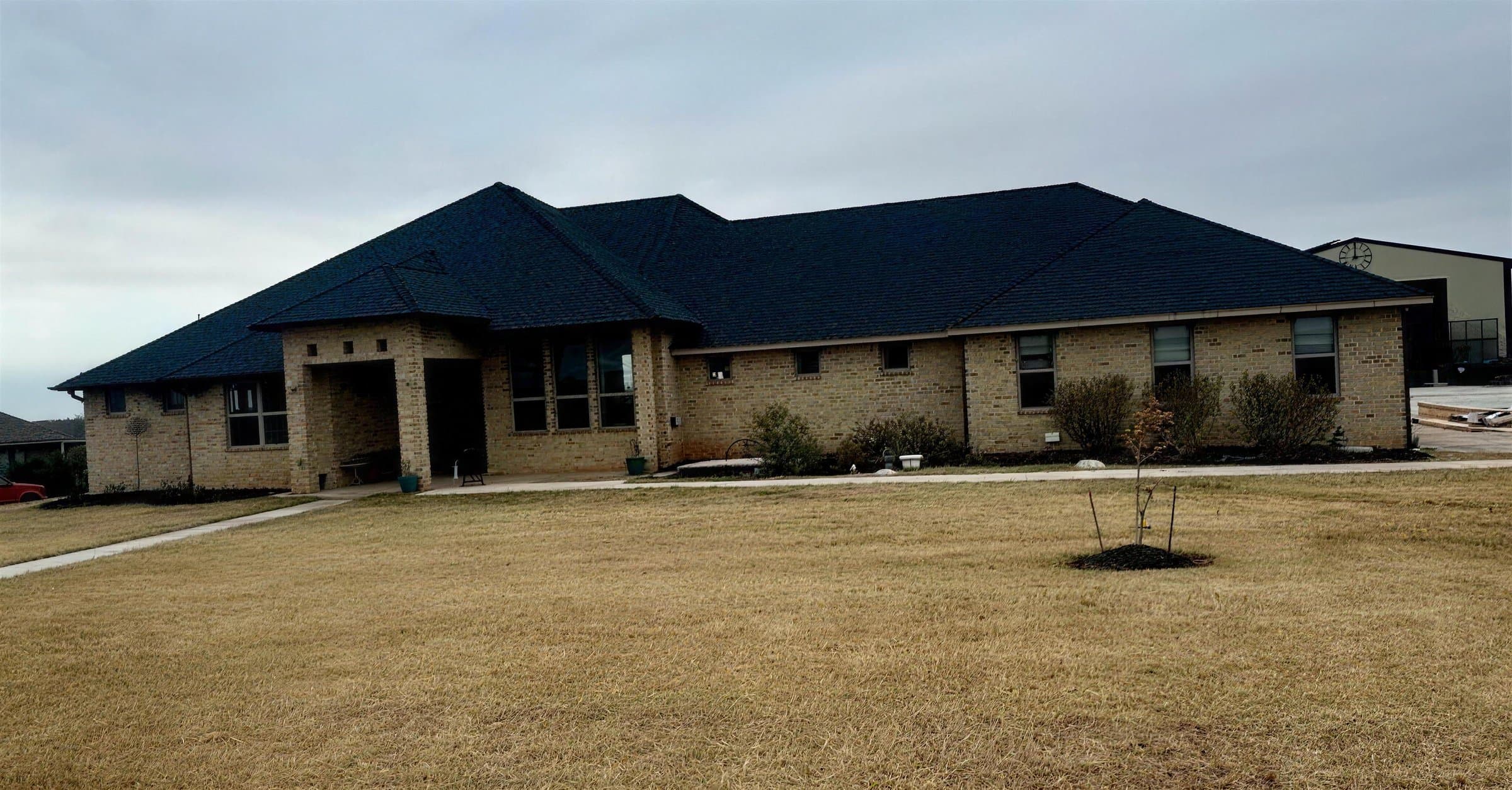 Single story brick home with a new black shingle roof