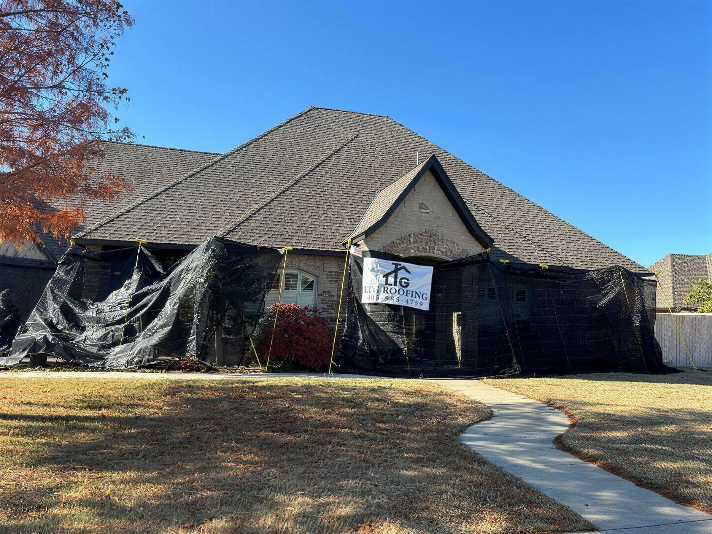 LTG Roofing banner on a home during a reroof, with black tarps protecting the walls and windows